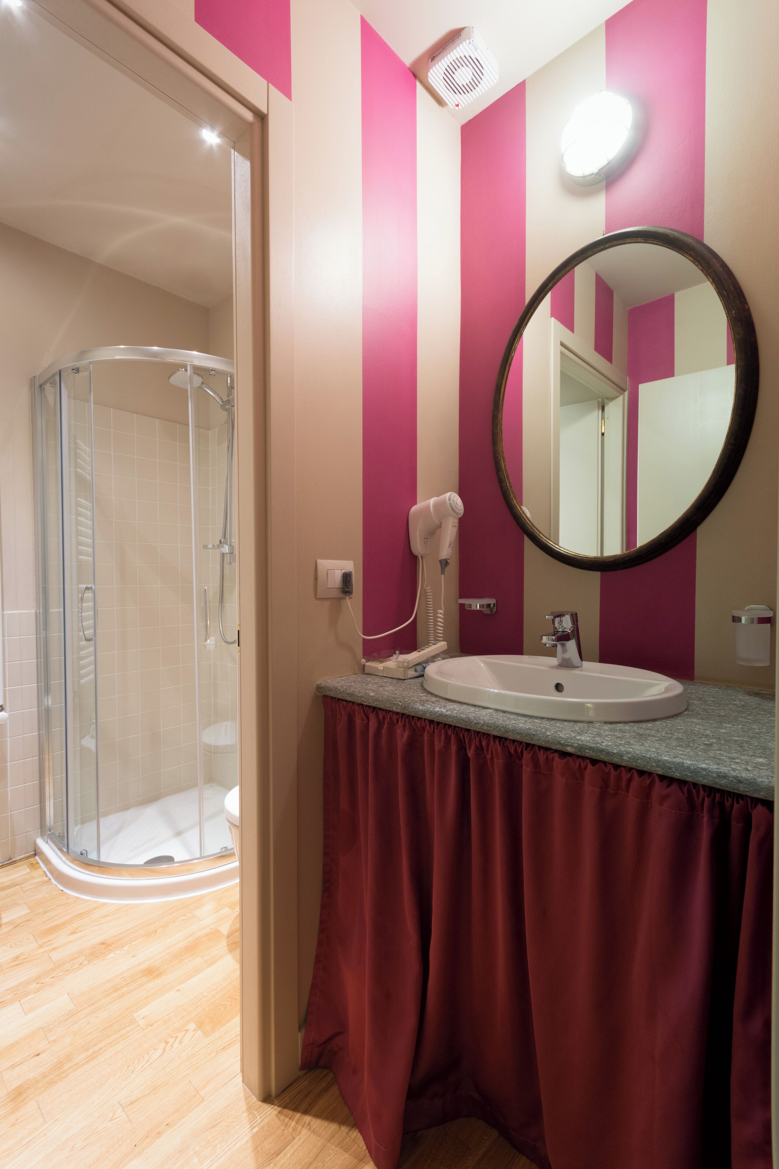 Une salle de bain avec une douche à parois de verre, un lavabo avec un meuble-vasque et un miroir.