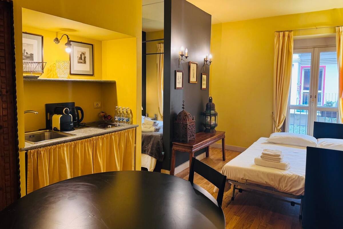 Una habitación compacta con kitchenette, una cama y una mesa de comedor.