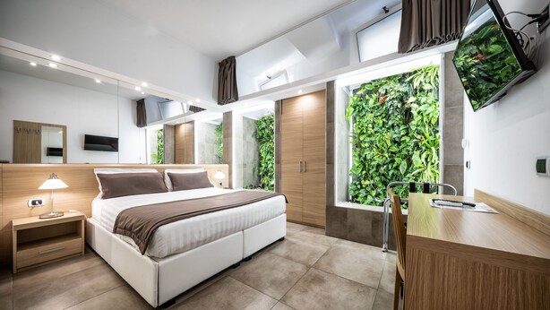 Een moderne slaapkamer met een groot bed, nachtkastjes, een bureau en een televisie.