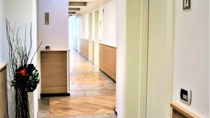 Een hotelhal met een receptiebalie, deuren met nummers en een modern design.