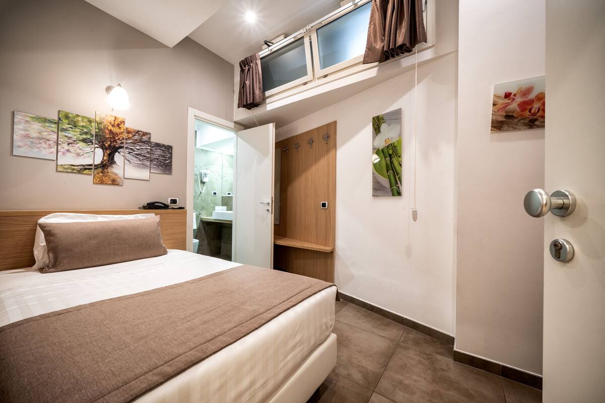 Une chambre d’hôtel moderne, dotée d’un grand lit, d’une armoire, d’une coiffeuse et d’œuvres d’art accrochées aux murs.