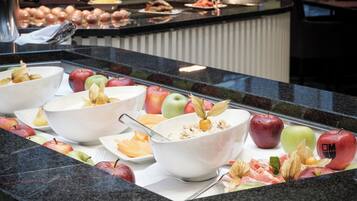 A buffet with various fruits and a bowl of cereal.