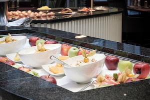 Un bufé con diversas frutas y un tazón de cereal.