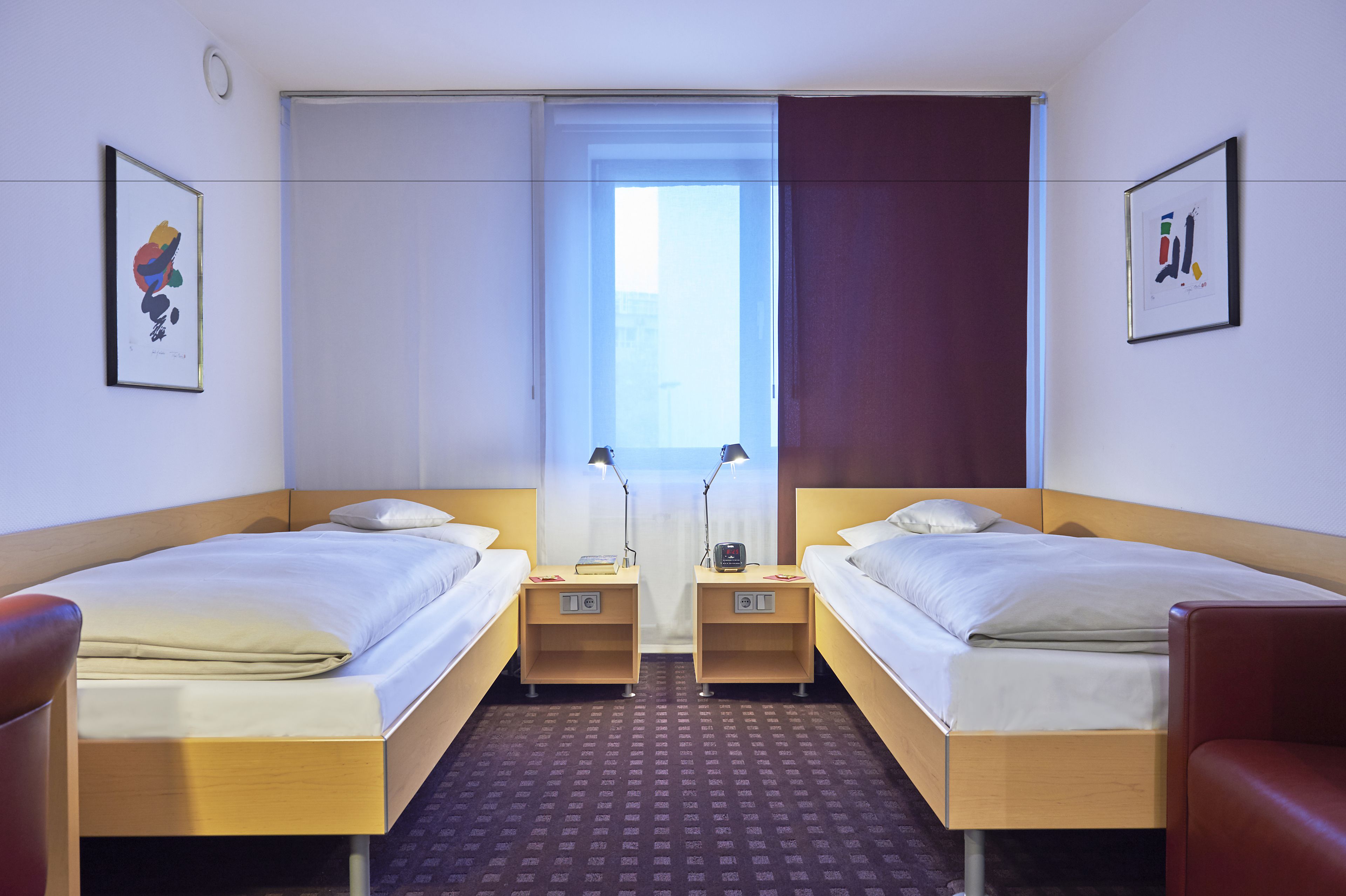 Habitación de hotel con dos camas individuales, una ventana con vistas y una puerta.