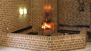 Ein Kamin aus Backsteinen mit Feuer, eine Bank und eine Statue an der Wand.