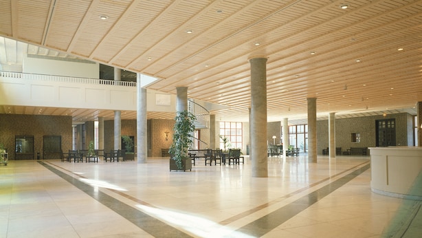 Eine geräumige Lobby mit hohen Decken, großen Säulen und einer zentralen Sitzecke.