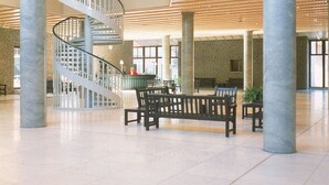 Eine großzügige Lobby mit einer zentralen Wendeltreppe, großen Säulen und Sitzbereichen.