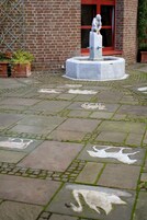 Un patio con una fuente de mármol, una estatua y un muro de ladrillo.