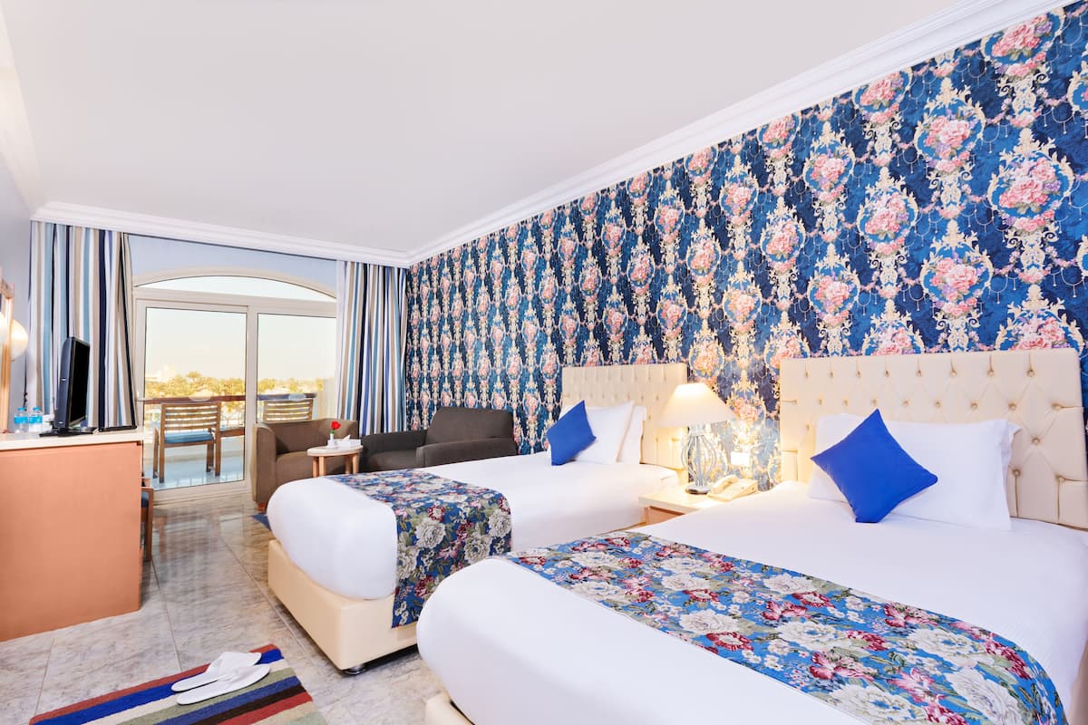 Una habitación de hotel con dos camas, un escritorio, una silla y un balcón con cortinas.