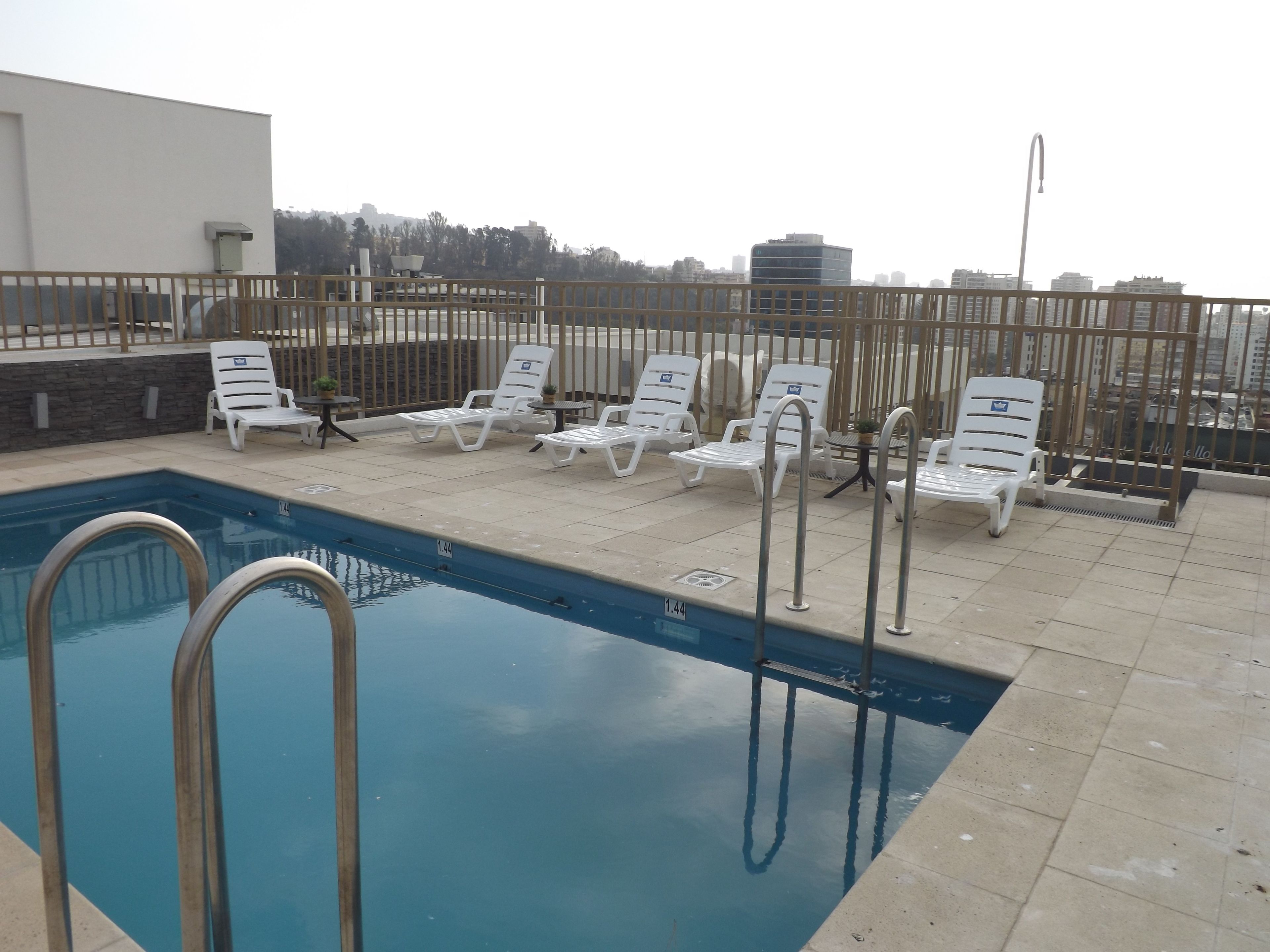 A rooftop pool area with lounge chairs and a swimming pool.