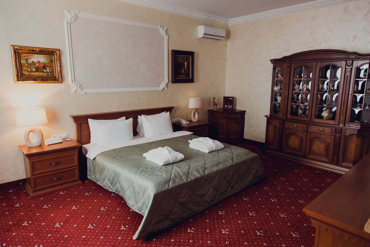 A hotel room with a bed, a nightstand, a lamp, a dresser, and a cabinet.