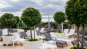 A rooftop lounge area with white lounge chairs and tables, surrounded by small trees and a city view. - Hotel France (Vinnytsia)