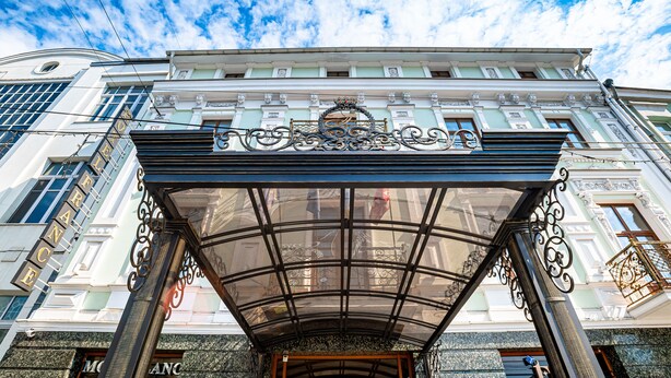 A grand entrance with a glass canopy and ornate metalwork, leading to a building with classical architecture and a prominent sign. - Hotel France (Vinnytsia)