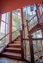 A wooden staircase with white balusters and a glass balustrade, leading to an upper floor.