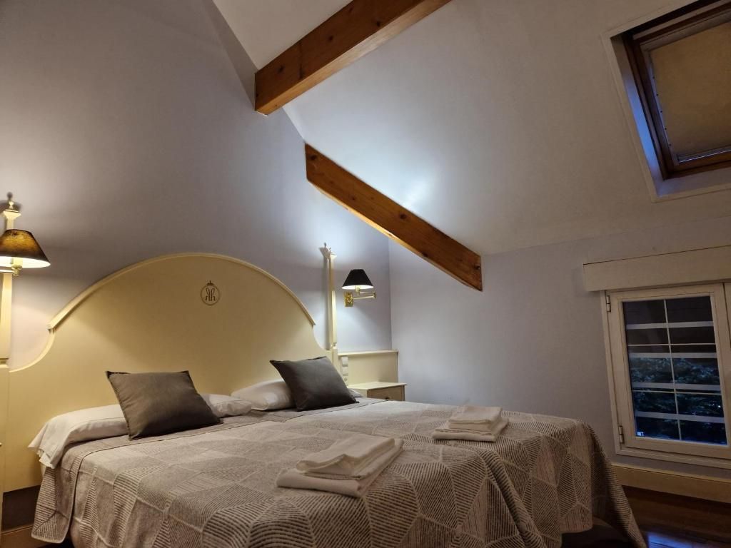 A bedroom with a bed, bedside tables, and a window.