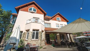 A two-story building with a stone facade, a balcony, and outdoor seating area with umbrellas. - Hotel Harrison Etxea (Amorebieta)