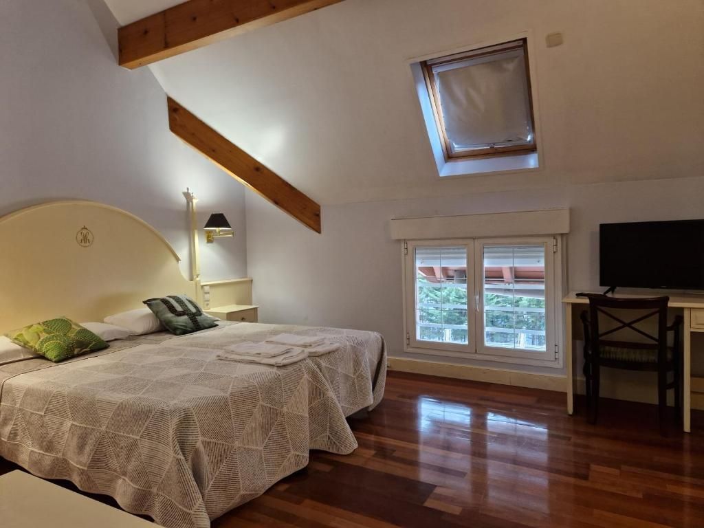 Un dormitorio con cama, escritorio, silla, ventana y tragaluz.