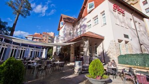 A hotel with outdoor seating, stone pillars, and a clear blue sky. - Hotel Harrison Etxea (Amorebieta)