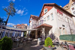 Un hotel con terraza al aire libre, pilares de piedra y un cielo azul despejado.
