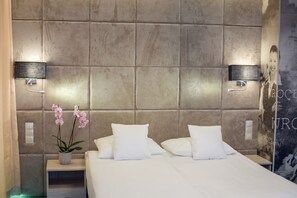 A modern hotel room with a large bed, two bedside tables, a vase with flowers, and a wall-mounted light fixture. - Citi Hotel's Wroclaw (Wroclaw)