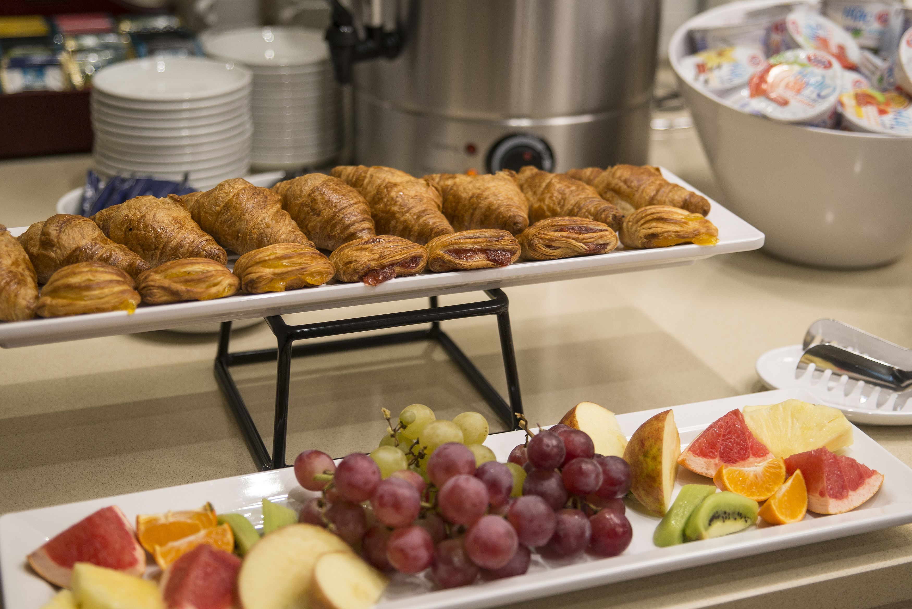 A buffet with croissants and a variety of fruits.