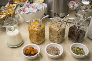 Un tavolo del buffet con diversi cibi, tra cui vasetti di cereali, frutta secca e noci.