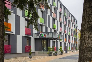 Un hotel dalla facciata moderna, con una serie di balconi caratterizzati da persiane colorate.