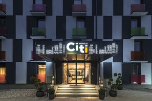 Entrada de un hotel con un cartel digital que muestra 'HOTELS Citi'.