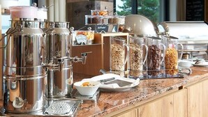 A buffet setup with various food containers and a coffee machine. - See- und Waldresort Gröbern (Muldestausee)