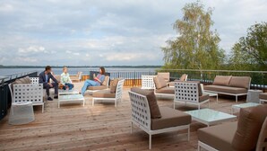 A deck with outdoor seating, a railing, and a view of the water. - See- und Waldresort Gröbern (Muldestausee)