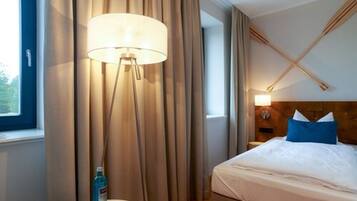 A hotel room with a bed, a bedside table, a lamp, and curtains.