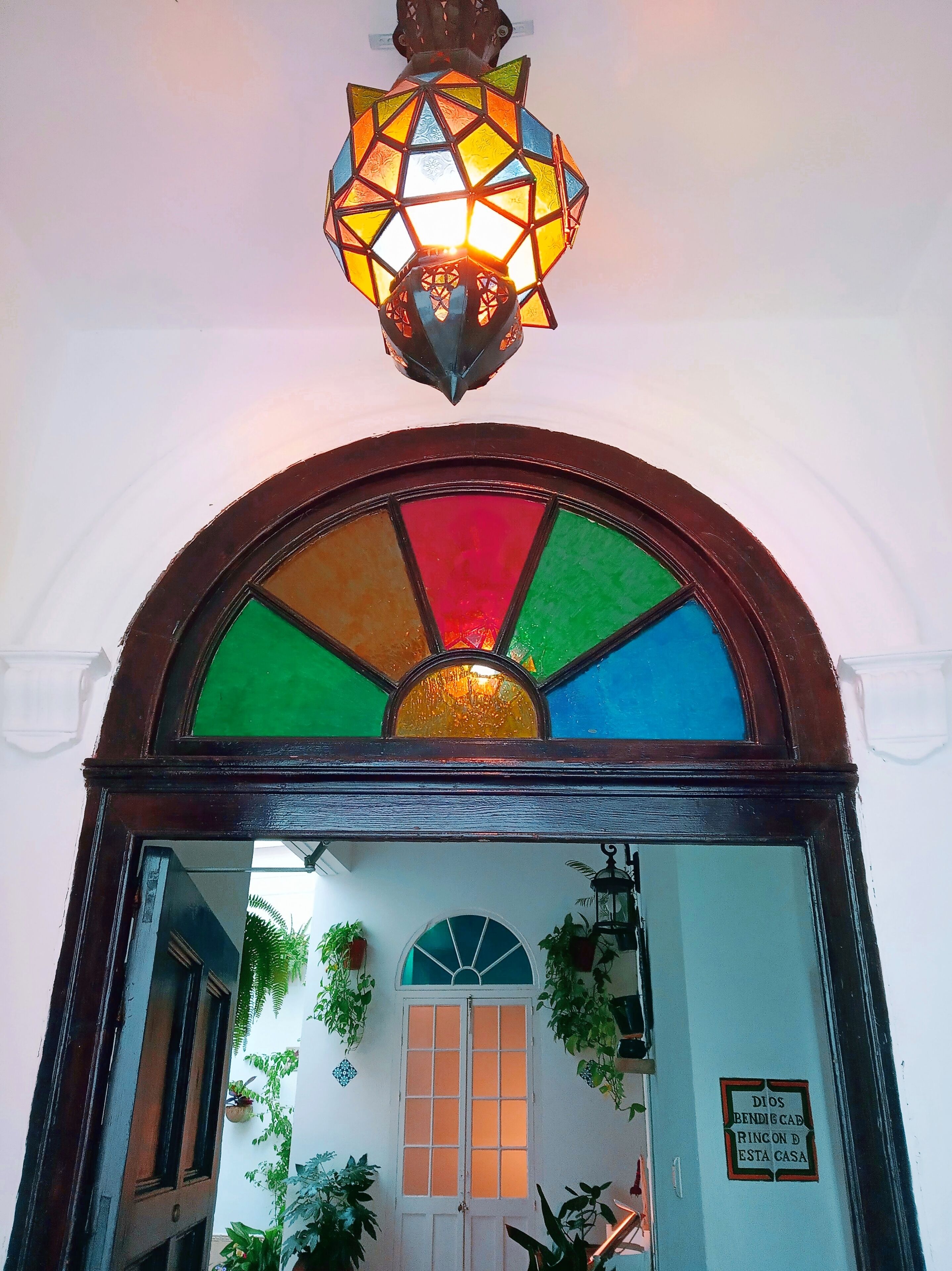 Una vidriera con un diseño geométrico y un aplique decorativo colgante encima.