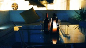 A table set with a bottle, glasses, and a candle, with a cityscape in the background.
