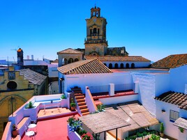 A historic town with a prominent clock tower, terracotta-tiled rooftops, and a mix of traditional and modern architecture.