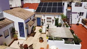 A courtyard with solar panels, potted plants, and a seating area.