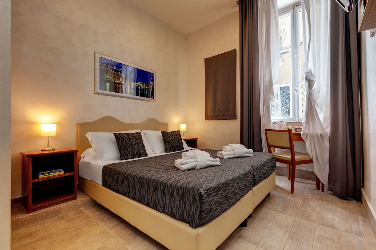 Una habitación de hotel con una cama, mesitas de noche, un escritorio y una silla.