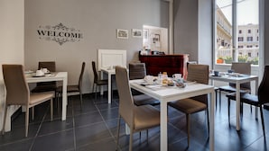 A modern dining area with two tables, chairs, and a 'WELCOME' sign on the wall. - AmoRoma (Rome)