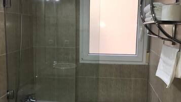 Un baño moderno con ducha envuelta en vidrio, bañera y retrete.