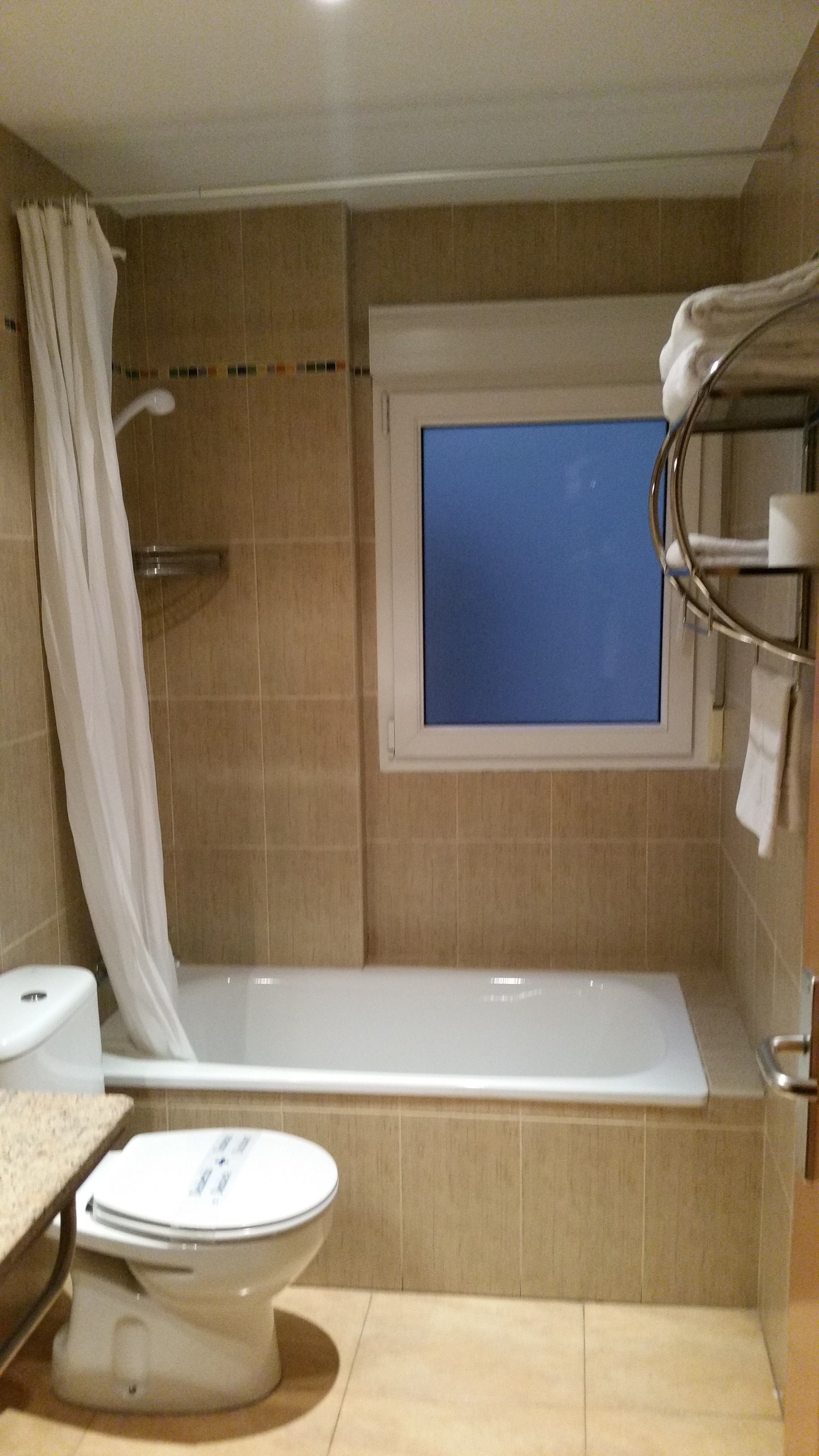 A bathroom with a bathtub, a toilet, and a window.