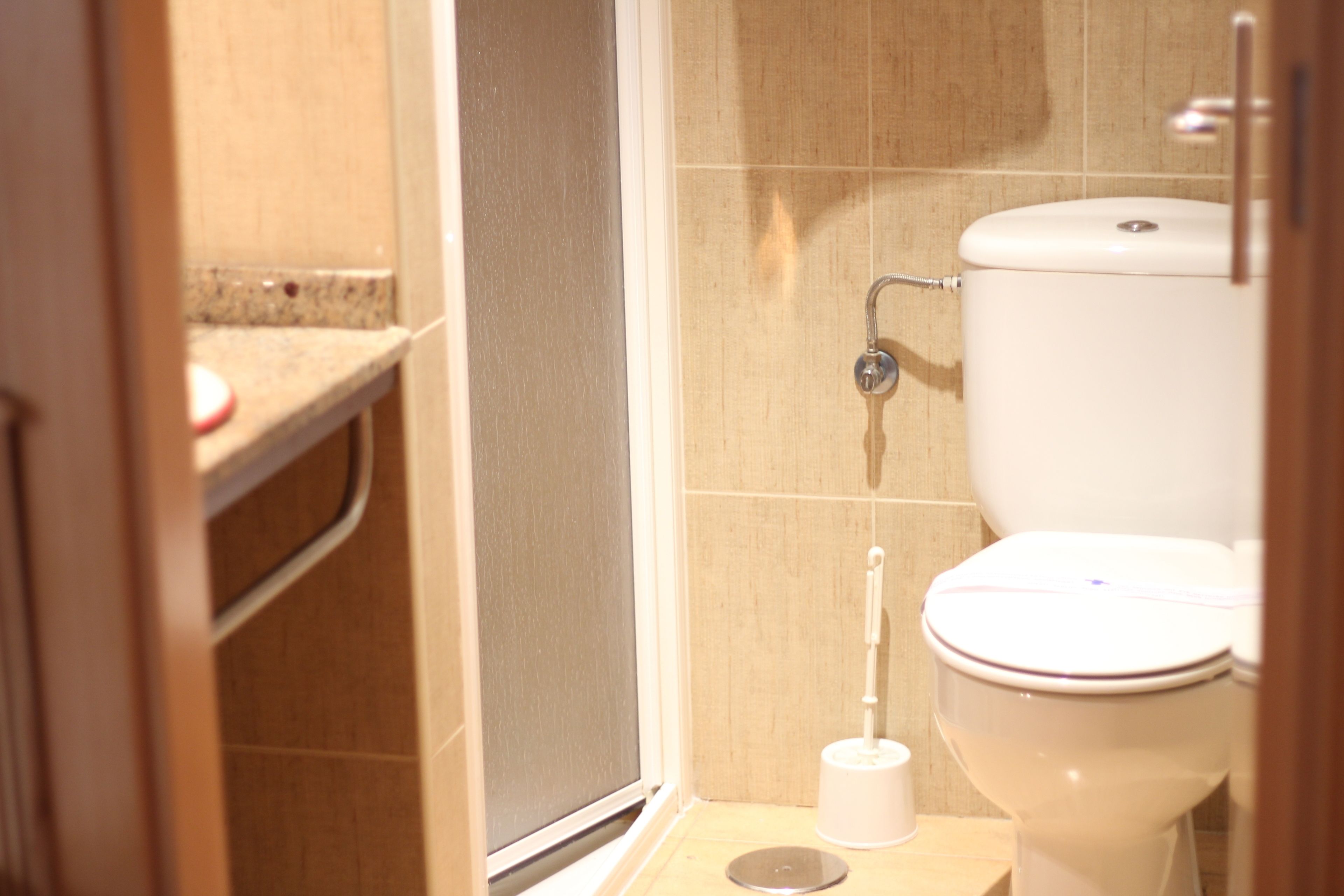 A bathroom with a toilet, a bidet, and a toilet paper holder.