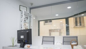 A reception desk with a computer monitor, a framed certificate on the wall, and a view of the outside through a window.
