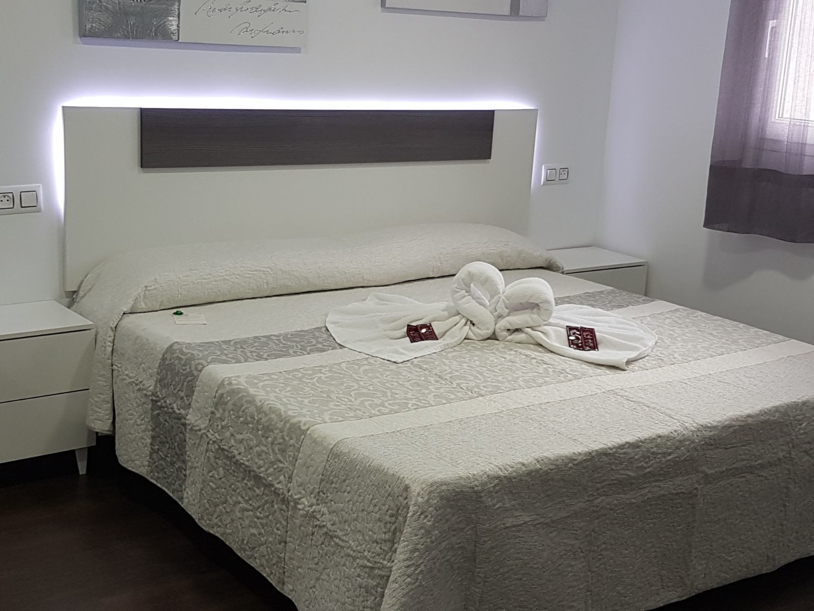 Un lit bien fait, avec une couvre-lit à motifs et deux serviettes pliées au centre.