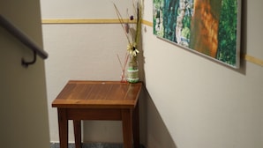 A wooden table with a vase of dried flowers and a small red candle.