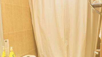 Un baño con inodoro, lavamanos y cortina de ducha.