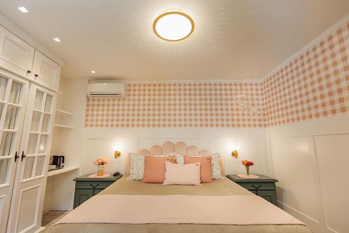 A bedroom with a large bed, two bedside tables, a wardrobe, and a ceiling light.
