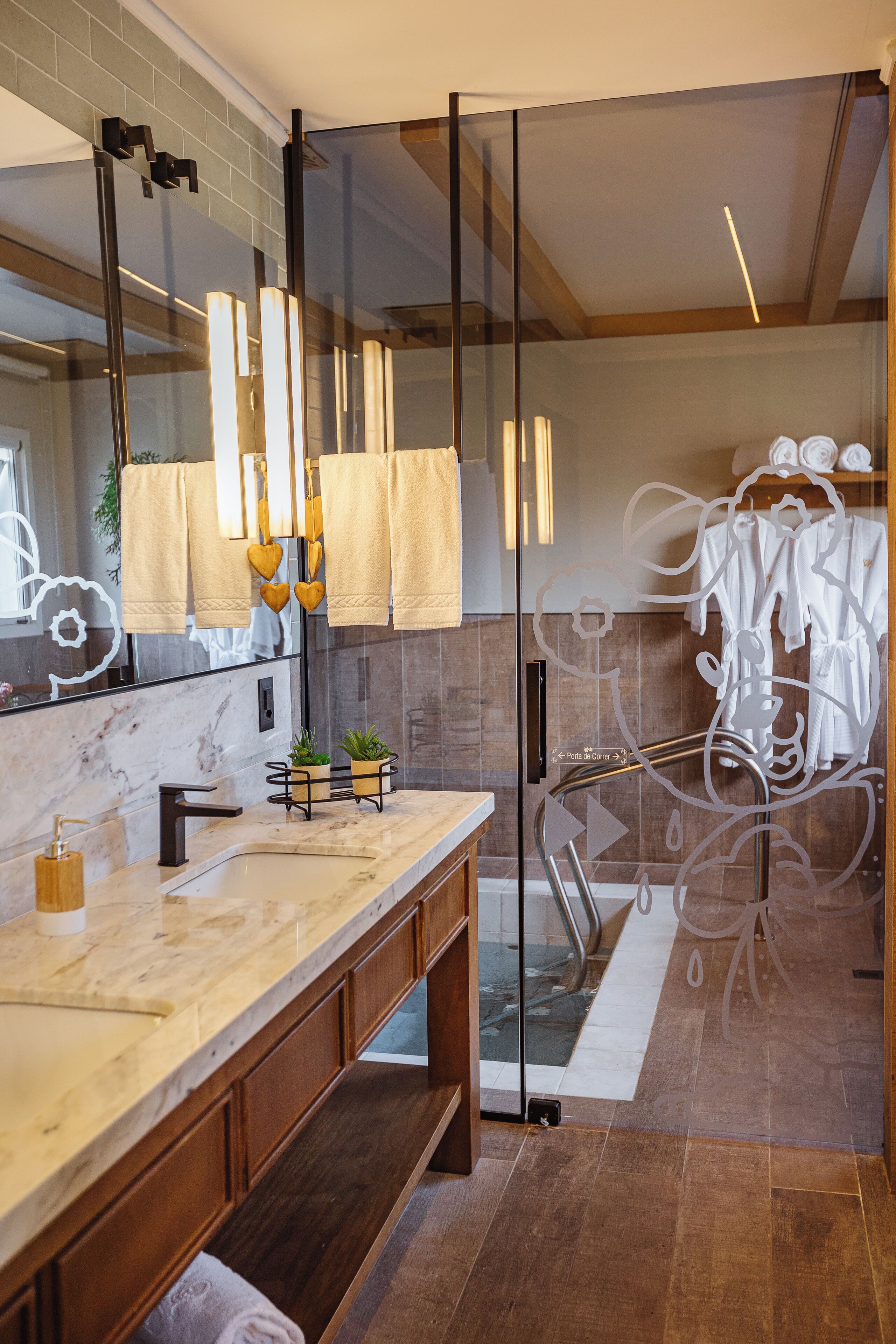 Un baño moderno con tocador de mármol, cabina de ducha con vidrio y tozaletas con toallas blancas.