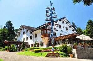 Um edifício tradicional com telhado inclinado, varanda com grade e placa indicando que é um hotel.