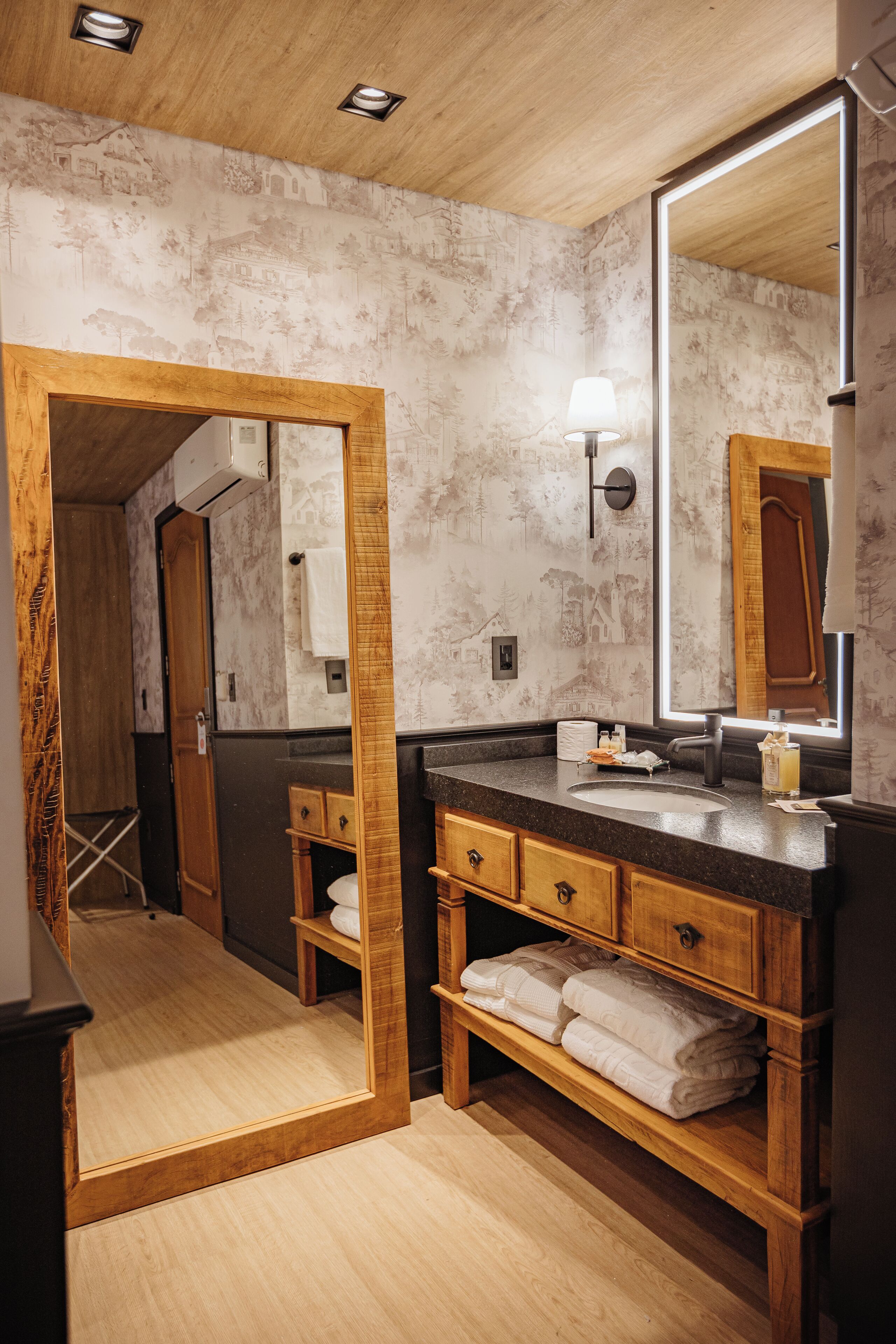 A bathroom with a wooden vanity, a large mirror, and a towel rack.