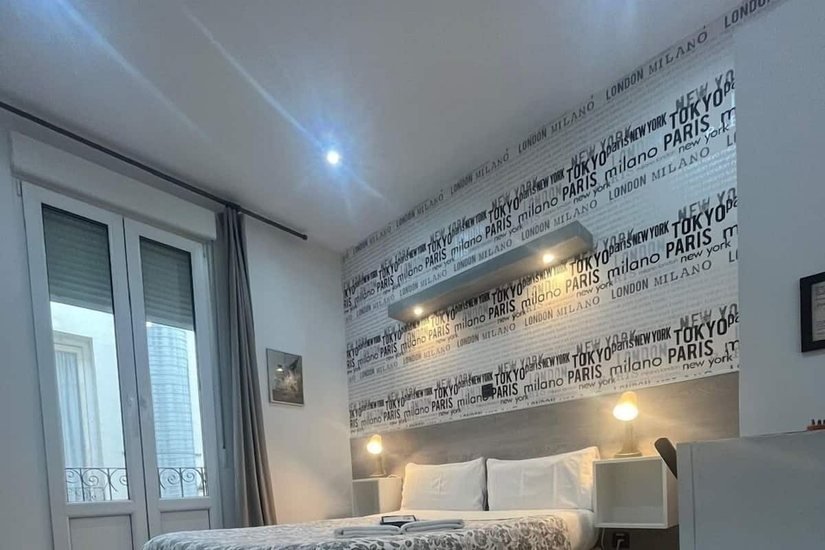 A modern bedroom with a bed, a nightstand, and a wall with city names.