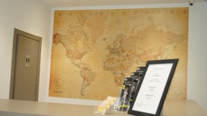 Una recepción con un gran mapa mundial, un cartel enmarcado y una puerta.